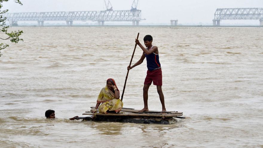 Flood-affected villagers use a temporary raft as they move through floodwaters after heavy rains at Patna district